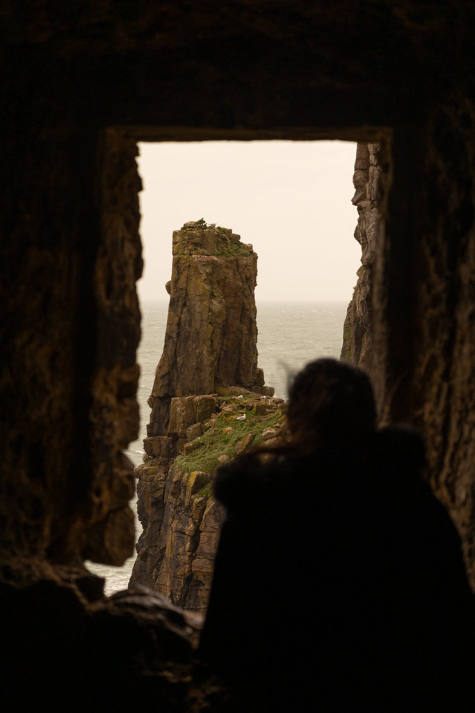 Rocky sea stack viewed through the opening of a coastal cave in Pembrokeshire