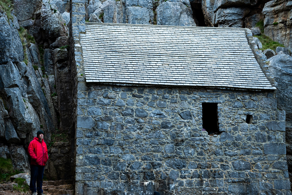 Small stone chapel nestled between steep limestone cliffs in Pembrokeshire