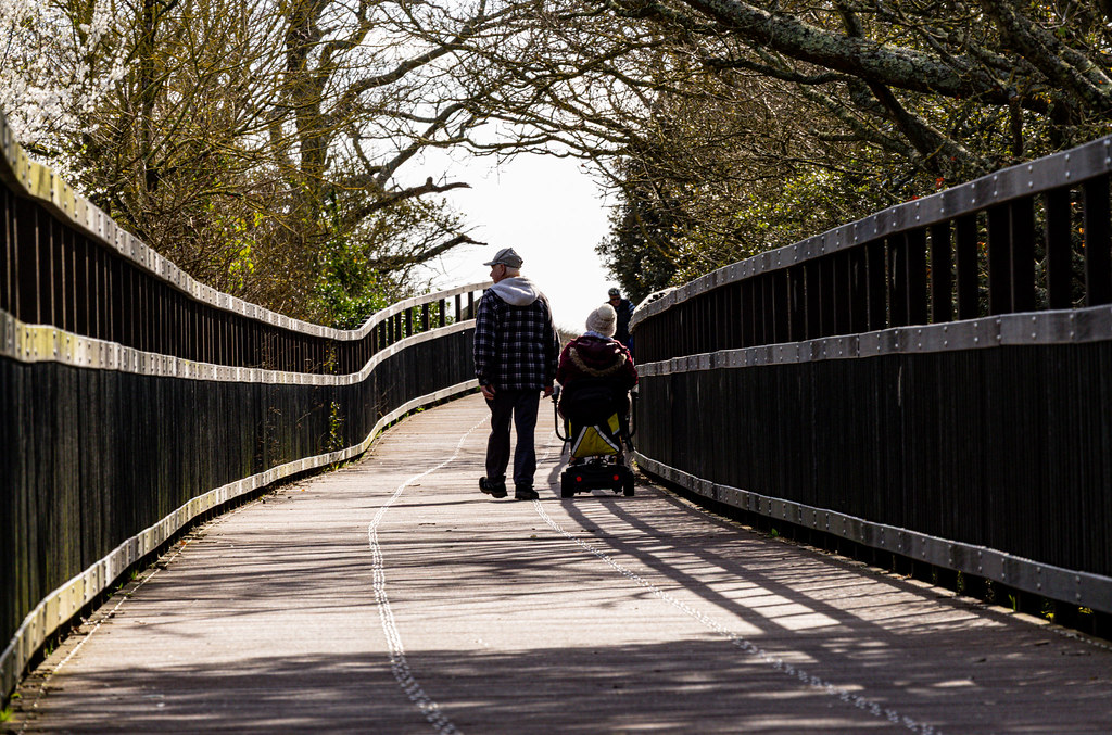Two walkers crossing the curved Goat Walk footbridge in Devon